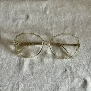 Vintage glasögonbåge från 80 talet, färgen är vattenklar, de är små stenar i kanten på bågen.  Kommer från en nedlagd Optikbutik, aldrig använd.  Hela bågens bredd 140 mm Glasets storlek, bredd 55 mm, djup 50 mm