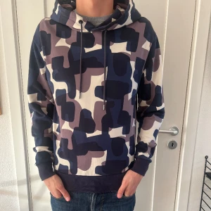 Hugo Boss Hoodie - En Hoodie från Hugo Boss Responsible Collection! Den är grymt snygg och påminner lite om valentino med sina kaxiga mönster! Den är så gott som ny förutom ett litet hål på framsidan (Bild 3)! Den är storlek S! Modellen på bilden är 184 cm!🤲🏻