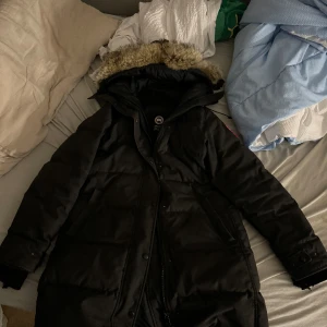 Canada Goose vinterjacka (dam) - Säljer min Canada Goose jacka som är använd endast 2 vintrar. Jackan är i god skick. Vid händernas slut så är det lite sönder tråd, men inget som märks av så. Det är bara de att dem har slitits. Luvan är i äkta rävpäls. Jackan köptes för 13500kr. 