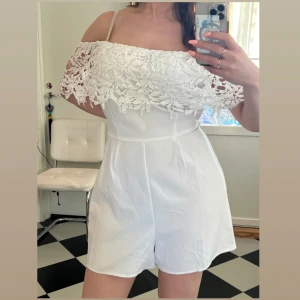 Helt ny vit jumpsuit - Tag kvar. Kan bäras som offshoulder eller täckta axlar. Sttetchig one piece. 94% polyester 6% elastan.  Står storlek 40, passar large, extralarge.  Största midjemått 82 cm, höft 104 cm (se bilder)  Slutsåld i butik.