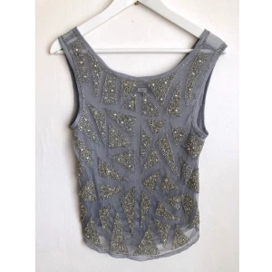 Ljusgrå fest linne, S 36/38, pärlor, strass, party, topp, art-deco, mesh - Oanvänt grått linne i dubbel mesh med pärlor och strass, observera att toppen är ganska tung fram. Finns några trådar som sticker ut. Mått får ej plats - fråga gärna!