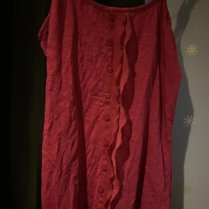 Lila linne från Vero Moda - Lila linne med knappar(endast detalj), volang och justerbara remmar. Köpt på brödet och fiskarna använt av mig en del. Mycket bra skick, inga defekter.