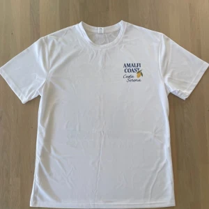 Vit Amalfi Coast t-shirt med citrontema - Vit t-shirt från Costa Serena med tryck fram och bak. Använd ett fåtal gånger.