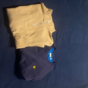 Beige half zip och marinblå Lyle & Scott - Två snygga tröjor! En beige sweatshirt med half zip och en marinblå crewneck från Lyle & Scott med klassisk gul logga på bröstet. Båda har rund hals och är perfekta för chill dagar. Marinblå tröjan har blå insida vid halsen för extra stilpoäng. Tröjorna är för små för mig båda ingår i priset. Vid eventuella frågor så är de bara att skriva.