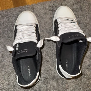 Svarta och vita sneakers från Numeris - Snygga svarta sneakers från Numeris med vita detaljer och grov, räfflad sula. Skorna har vita snören, vit tå och häl samt kontrasterande vita sömmar. Ovandelen är i ett matt material och sulan är extra chunky för en modern look. De har inte använts bara testats. De är såklart äkta kan visa order nummer samt kvitto. Säljer de på grund av att de är för stora. Säljer skorna även för 200 kr billigare än online.