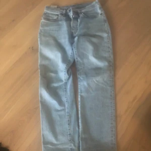 Levi's 501 ljusblå jeans straight fit - Klassiska Levi's 501 jeans i ljusblå denim med rak passform och femficksdesign. Byxorna har knappgylf och den ikoniska läderpatchen bak i midjan. Perfekta för en avslappnad och tidlös stil.