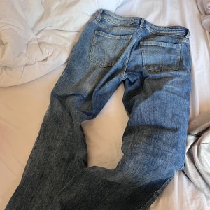 Blå straight jeans från Bershka - Säljer ett par blå jeans från Bershka i storlek 34. Modellen har klassisk femficksdesign, låg midja och raka ben med en chill straight fit. Jeansen är gjorda i jeansmaterial och har snygga slitningar för en avslappnad vibe.
