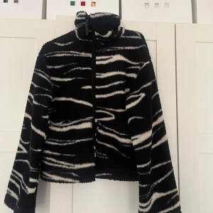 HM teddyjacka - Säljer en svartvit teddyjacka i storlek XS med zebramönster från HM. Jackan har hög krage, dragkedja framtill och två fickor💕💕Väldigt bra skick 
