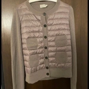 Moncler cardigan  - Snygg beige/brun quiltad cardigan jacka  från Moncler med stickade ärmar och två stickade fickor framtill. Fint skick, några trådar som sticker ut på ärmen men går enkelt att få tillbaka med en virknål. I övrigt fint skick, inga hål eller liknande. Storlek L men passar även mindre då de är små i storleken