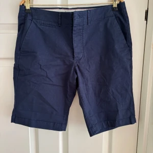 Marinblå chinos shorts herr - Snygga marinblå shorts med klassisk rak passform och midwaist. Perfekta för sommardagar, med praktiska fickor och stilren design. Passar dig som gillar enkel och clean stil.