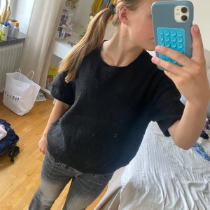 Svart stickad tröja från H&M - En svart stickad tröja från H&M i storlek M. Tröjan har korta ärmar och en rund halsringning. Den är enkel och stilren, perfekt att matcha med jeans eller kjol. Materialet är mjukt och ger en avslappnad vibe.