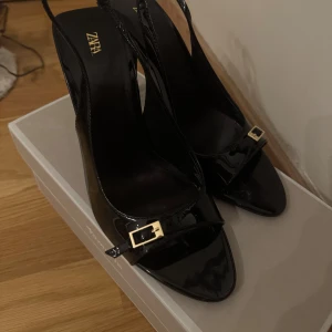 Svarta lackpumps från Zara med spänne - Klackskor från zara i storlek 38. Använda en gång.