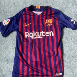FC Barcelona matchtröja Nike S - Säljer en officiell FC Barcelona matchtröja från Nike i storlek S. Tröjan har klassiska blå och röda vertikala ränder, klubbmärke på bröstet, Rakuten-tryck fram och UNICEF-tryck bak. Korta ärmar och tillverkad i lätt Dri-FIT-material för bästa komfort.