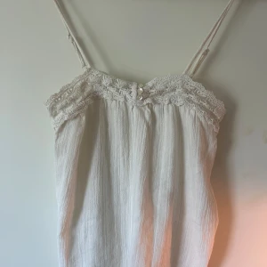 Vit linnetopp med spets från Promod - Supersöt vit linnetopp från Promod med tunna axelband, spetsdetaljer och små pärlor framtill. 💞💞