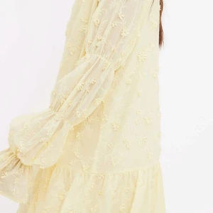 Ljusgul blommig kortklänning med volang - Superfin ljusgul viral kortklänning med blommigt broderi och transparenta, puffiga långärmar. Klänningen har volang nedtill, öppen rygg med knyt och en loose passform. Perfekt för sommarens alla tillfällen, riktigt söt och trendig vibe. Pris kan diskuteras!🥰