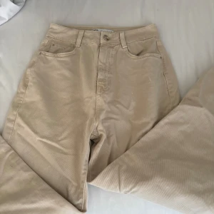 Beige manchesterbyxor från Zara - Snygga beige manchesterbyxor från Zara i storlek 34. Byxorna har hög midja, raka ben och klassisk femficksdesign. Mjukt manchestertyg som ger en chill och trendig vibe. Perfekta att styla med sneakers eller boots för en cool look.