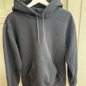 Svart hoodie från H&M XS - Svart hoodie från H&M i relaxed fit med huva och snörning. Tröjan har en stor magficka och långa ärmar, perfekt för chill dagar.