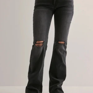 Svarta bootcut jeans med slitningar - Snygga svarta jeans med bootcut passform och slitna hål över knäna.  Ny pris 699! Storlek 34 