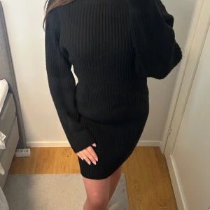 Svart ribbad stickad klänning - Svart ribbstickad klänning med lång ärm i storlek M från H&M. Modellen är kort och har en båthalsringning. Använd fåtal gånger💞
