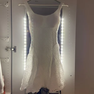 Vit sommarklänning med öppen rygg - Superfin vit kort klänning med broderade detaljer och små hålmönster. Klänningen har breda axelband, markerad midja och en söt rosett i ryggen. Perfekt för sommarens alla tillfällen och ger en romantisk vibe. Klänningen har en öppen rygg och paddar i fram. Köpt i Italien och använd en gång så i nytt skick💕🤍