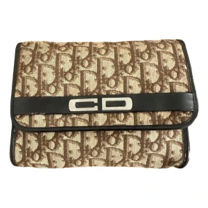 Dior väska - brun kuvertväska från Dior med klassiskt monogrammönster och silverfärgad CD-detalj framtill. Det är en kuvertväska som jag köpt kedja till. Kedjan medföljer. Äkthetsbevis finns. Köpt på Vestiaire collective. Skriv om du är intresserad. Påse medföljer 