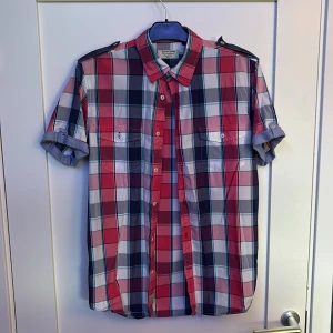 Rutig kortärmad skjorta från Matinique - Snygg rutig skjorta från Matinique i färgerna röd, blå, vit och grå. Skjortan har korta ärmar med knappdetalj, två bröstfickor och klassisk krage. Perfekt för dig som gillar en avslappnad men stilren look.