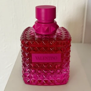 Valentino parfym 100ml rosa flaska - Snygg parfym från Valentino i en cool, fyrkantig flaska med nitar och struktur i starkt rosa glas. Flaskan rymmer 100 ml och är limited edition Born in roma och säljs för 1850kr nypris. ALDRIG använd men (obs saknar förpackningen) men packeterar in den väl i något annat. 
