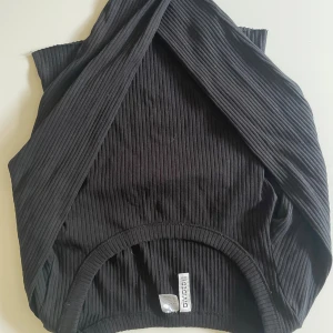 Svart ribbad omlottopp H&M Divided - Svart ribbad omlottopp från H&M. Lite magtröja!!