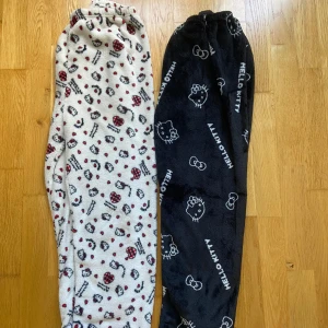 Två par Hello Kitty pyjamas byxor, svart & vit - Två par supermjuka fleecebyxor med Hello Kitty-motiv. Ena paret är svart med vita Hello Kitty-tryck och text, det andra är vitt med röda och svarta Hello Kitty-huvuden, hjärtan och rosetter. Ett par kostar 150kr och båda tillsammans blir 280kr. Köp gärna båda tillsammans!💞