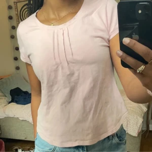 Ljusrosa t-shirt med veck - Säljer en jättesöt ljusrosa t-shirt med korta ärmar och fina veckdetaljer vid halsringningen🤗 Skön och enkel modell i mjuk bomull, perfekt till sommaren☀️ Omsydd till storlek S
