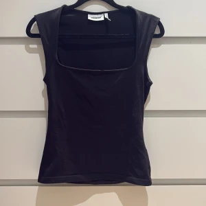 Svart ärmlös topp från Weekday - Svart, stilren ärmlös topp från Weekday med fyrkantig ringning, och sitter ganska tight💞Använd fåtal gånger 