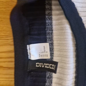 Randig långärmad tröja från Divided - Säljer en ribbad långärmad tröja från Divided med breda ränder i vitt, marinblått, grått och vinrött. Tröjan har en rund halsringning och är figurnära i modellen. Perfekt för dig som gillar en stilren men färgglad look.