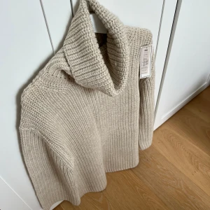 Beige polotröja från Kay Day  - Nypris 1299. Säljer en chunky beige stickad polotröja från Kay Day Kappahl. Tröjan har en hög, bred polokrage och är ribbstickad i mjuk ull. Perfekt för lager-på-lager och ger en clean, chill vibe till din höst- eller vinterlook.