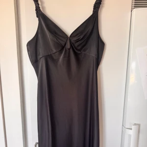 Svart satin klänning från adoore - Supersnygg svart klänning i satin. Perfekt till en utgång med en eller utan blazer!!! Är vanligtvis en L denna storlek är 48. Använd endast 3 gånger