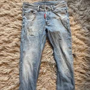 Dsquared jeans - Säljer ett par ljusblå jeans från Dsquared2 med klassisk femficksdesign och snyggt slitna detaljer. Jeansen har normal passform och är tillverkade i bomull. Perfekta för dig som gillar en avslappnad och trendig look. Skick 7/10 då vänster ficka är sönder och de är lite slitningar i baksidan av jeansen som man ser på sista bilder därav priset. Bara att höra av sig vid minsta fundering!