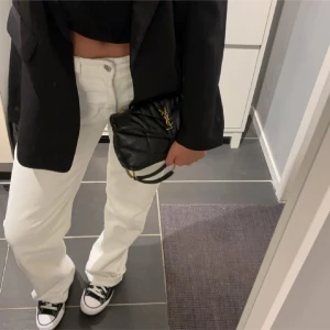 Vita raka jeansbyxor - Säljer ett par vita jeansbyxor med rak passform och normal midja. Byxorna har klassisk femficksdesign och stängs med knapp och dragkedja. Perfekta för en clean och stilren look.