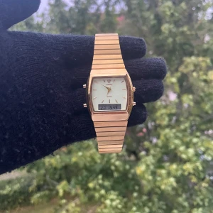 Guldig digital- och analogklocka Lorus - Snygg guldig klocka från Lorus med både digital och analog visning. Klockan har en rektangulär urtavla med guldfärgade detaljer och länkarmband i metall. Perfekt för dig som gillar retrostil och vill ha både klassisk och modern känsla.