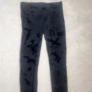 Svarta camo leggings med hög midja - Snygga svarta leggings med mörkgrått camo-mönster och hög midja. Stretchigt material som sitter tight och bekvämt, perfekta för träning! Stilren look som funkar till sneakers och hoodie. Passar folk med både storlek M & L