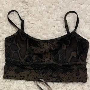 Aim’n sporttop - En mörkgrön/ brun sporttop med likande ormmönster från aim’n! Använd max 2 gånger så den är så gått som ny! Smala band och kommer med två inlägg. 