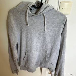Ljusgrå hoodie  - Säljer en ljusgrå hoodie från stadium med en ficka där fram och en luva. Tröjan har långa ärmar och ribbade muddar. Den är använd en del gånger, men det är inget som märks av. Själva märket på hoodien (soc)  har försvunnit men man ser fortfarande mönstret av det. 