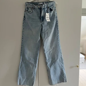 Ljusblå raka jeans från Zara, stl 38 - Säljer ett par ljusblå Wide/straight leg jeans från Zara i storlek 38. Dem är ganska true to size men skulle säga att dem passar en strl 40-42 för en mer oversized look. I nytt skick, inte använda samt att prislappen är kvar! För referens är jag ca 176 cm lång.