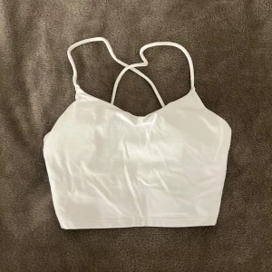 Vitt träningslinne med öppen rygg - Ett vitt träningslinne med öppen rygg som är perfekt till träning, den är i croppad passform och kan även användas till tränings bh. Har tyvärr inga bilder med den på. Hör av dig om du har frågor!💕