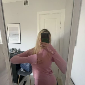 Rosa tröja från Lindex - Säljer en söt rosa tröja från Lindex med långa ärmar och dekorativa knappar vid ärmsluten. Perfekt för en stilren och bekväm look. 💖