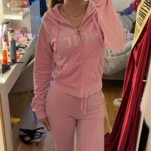Rosa Juicy Couture set med paljetter - Säljer ett rosa Juicy Couture set med ”juicy” tryck på framsidan av koftan och baksidan av byxorna. Tröjan är i storlek S. Byxorna är i storlek XXS, men är rätt så stretchiga då de passar mig som normalt vis har stl XS-S. Det är väldigt bekvämt sätt och mycket skönt material. Vid frågor är det bara att höra av sig!💓💓