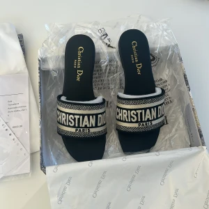 Svarta sandaler från Christian Dior - Snygga svarta tofflor från Christian Dior med broderad rem. Aldrig använda endast testade då de var för små för mig, skriv för fler bilder. Storlek 38