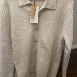 Stickad kofta från Pier one. - Säljer en stilren off-white kofta från Pier One. Aldrig använd med lappar kvar. Tillverkad av återvunnen polyester.