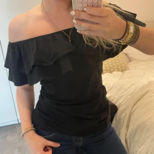 Svart offshoulder topp - Snygg svart offshoulder topp med volangdetaljer. Perfekt för en stilren look. Passar bra till både jeans och kjol❣️ egentligen en klänning men har vikt upp - men inget som syns!!