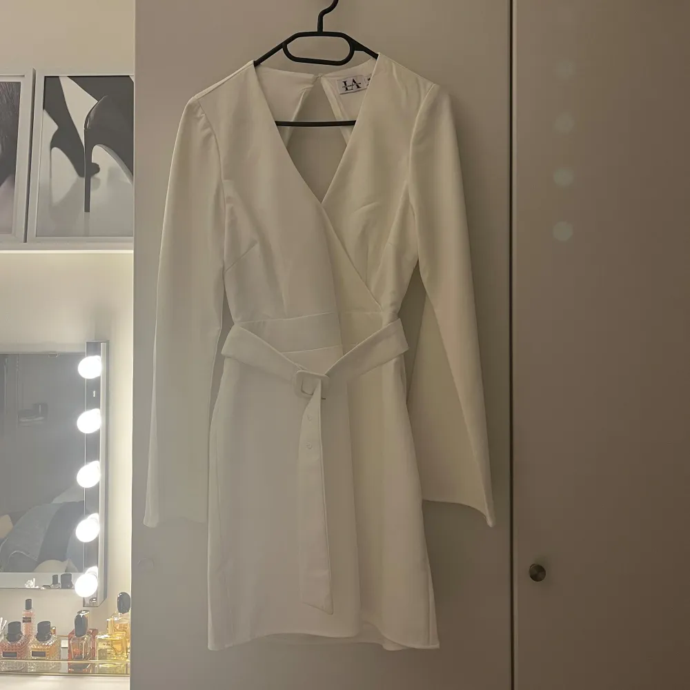 Vit omlottklänning från NA-KD X Linn Ahlborg. Klänningen har långa ärmar och en v-ringad design med öppen rygg. Perfekt för studenten eller en utekväll. Aldrig använd. . Mekot.