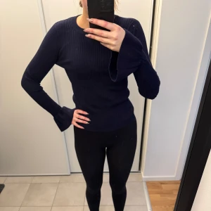 Mörkblå ribbad tröja från Lindex - Säljer en snygg mörkblå ribbad tröja från Lindex. Den har långa ärmar med en unik volangdetalj vid ärmsluten. Perfekt för både vardag och festliga tillfällen. Superbekväm och stilren!