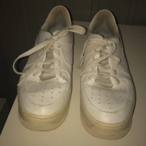 Vita Nike sneakers - Säljer ett par klassiska vita Nike sneakers med snörning. Skorna har en rund tå och perforerade detaljer på ovansidan för ventilation. Perfekta för en stilren och sportig look.